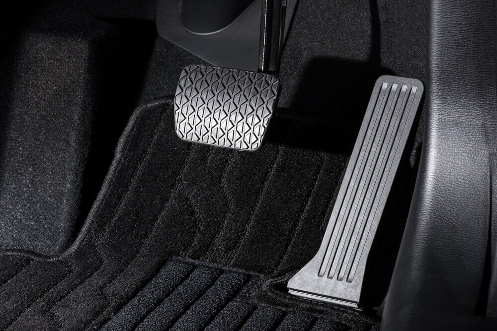 close up of an automatic car's two pedals with black carpet surrounding them