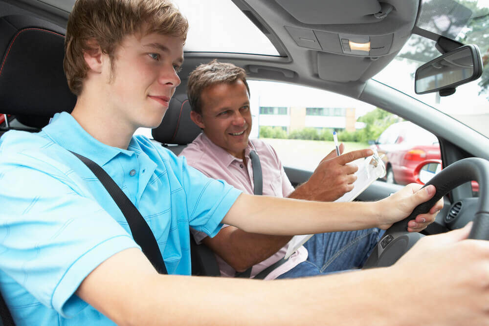 A driving school Mandurah instructor assessing a young boy for his driving test