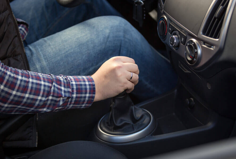 close up of a male driving student with his hand on the gear select leaver of a manual car