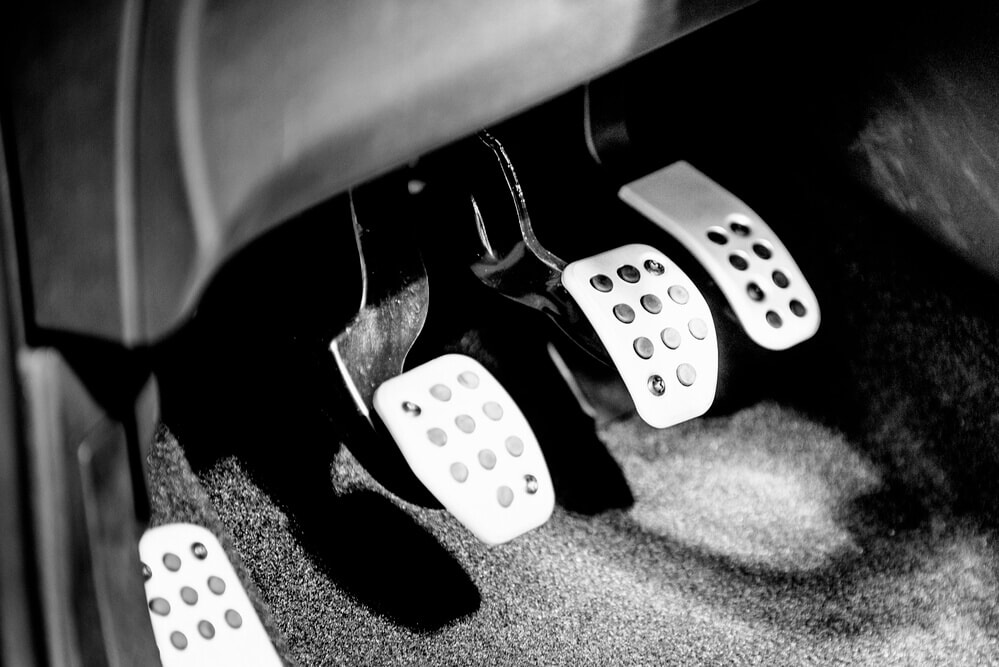 close up of the three pedals of a manual car that have silver surfaces on them