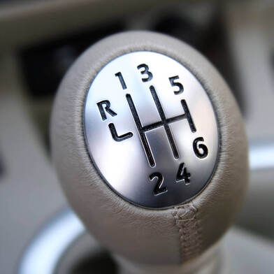 close up of a 6 speed manual car's shifting knob with grey leather